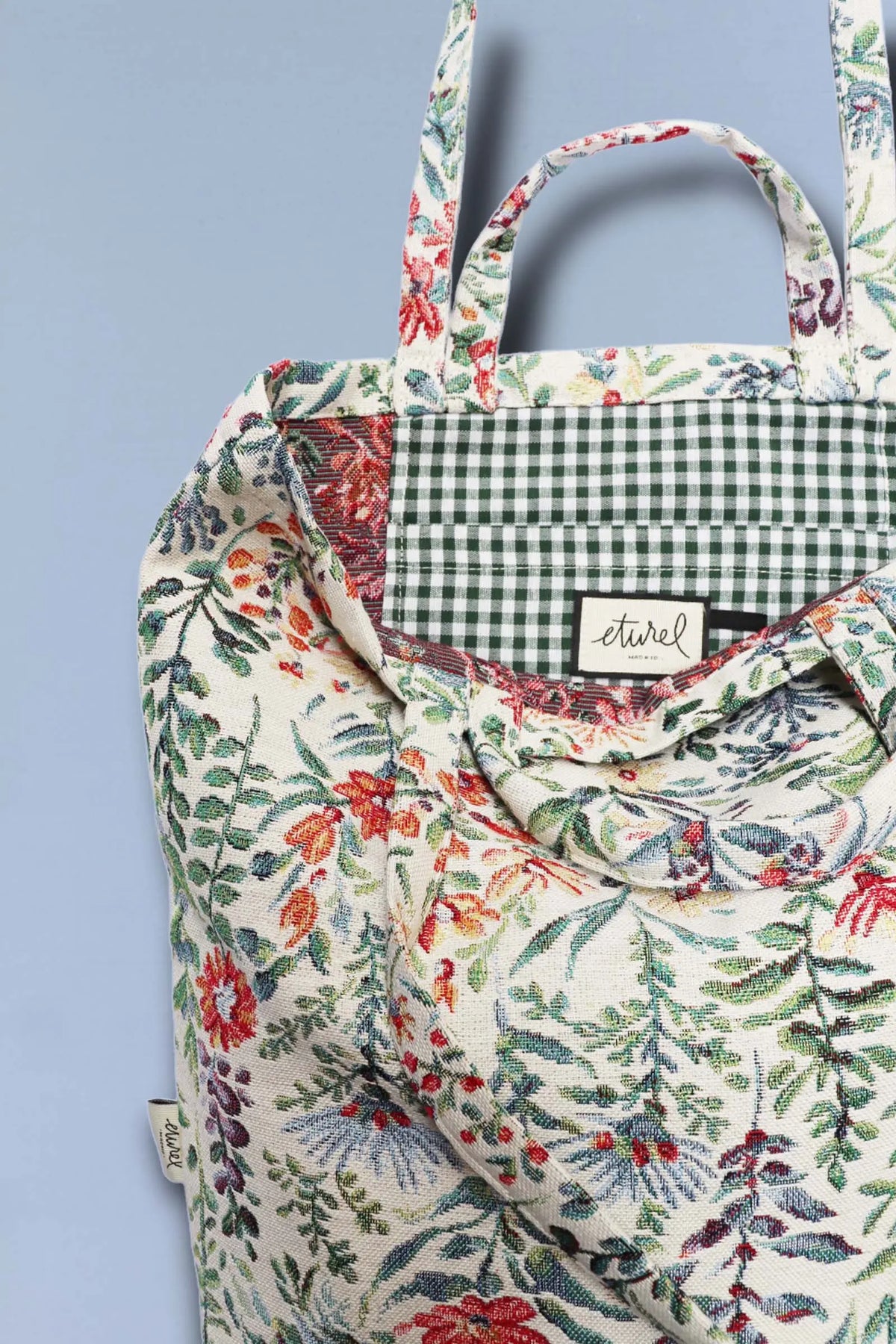 Tote bag in cream jacquard fabric with a colorful azalea floral pattern and a green checkered interior lining.