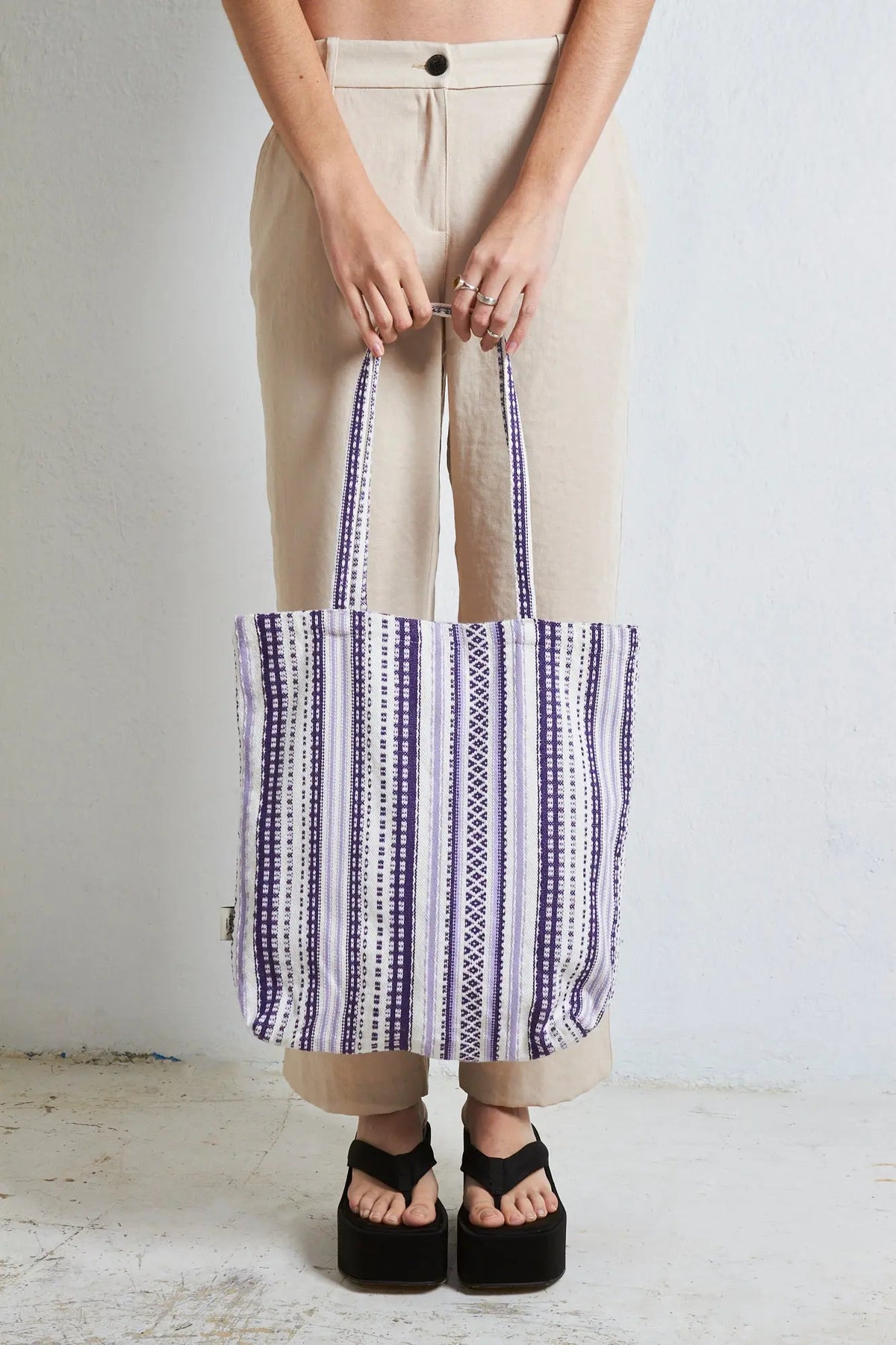 Tote bag de tela con estampado alpujarreño en tonos malva y blanco, de estilo artesanal y asas largas.