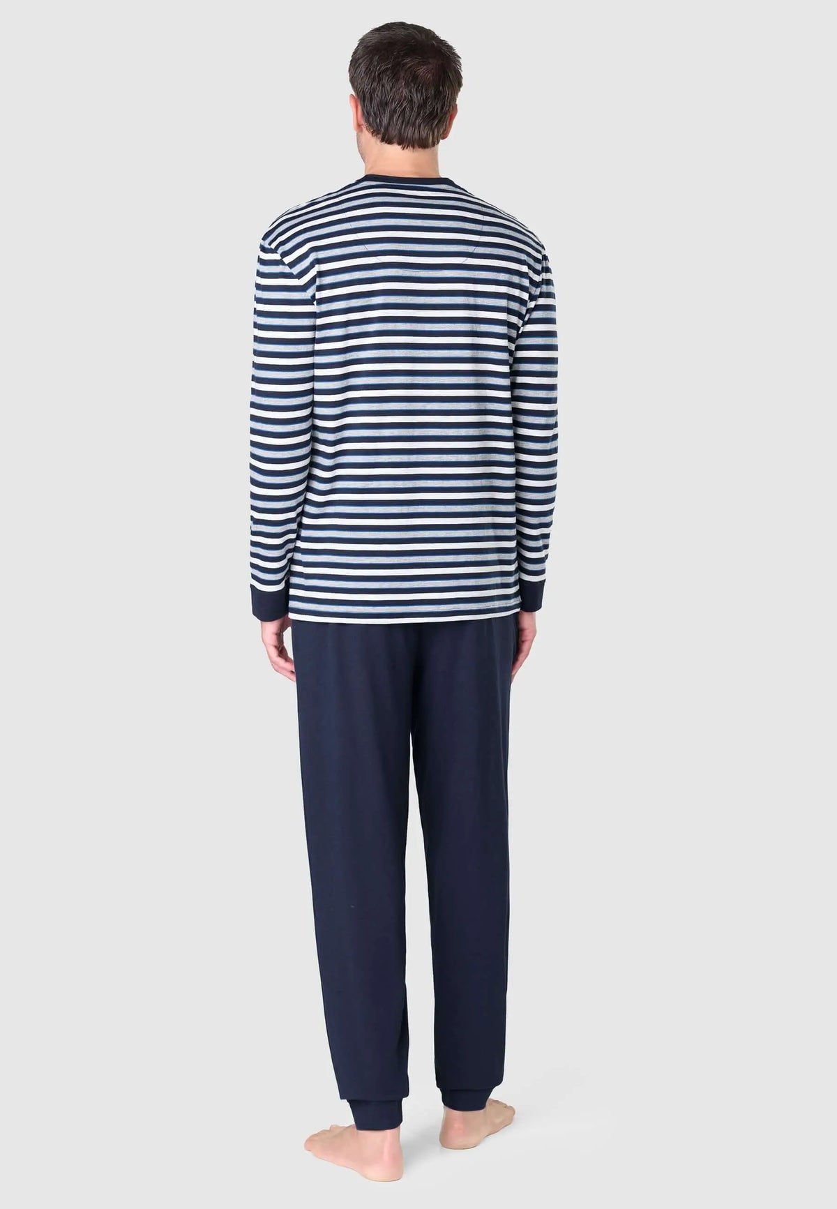 Hombre de espaldas con pijama: camiseta de rayas horizontales en tonos azules, grises y blanco, y pantalón azul marino.