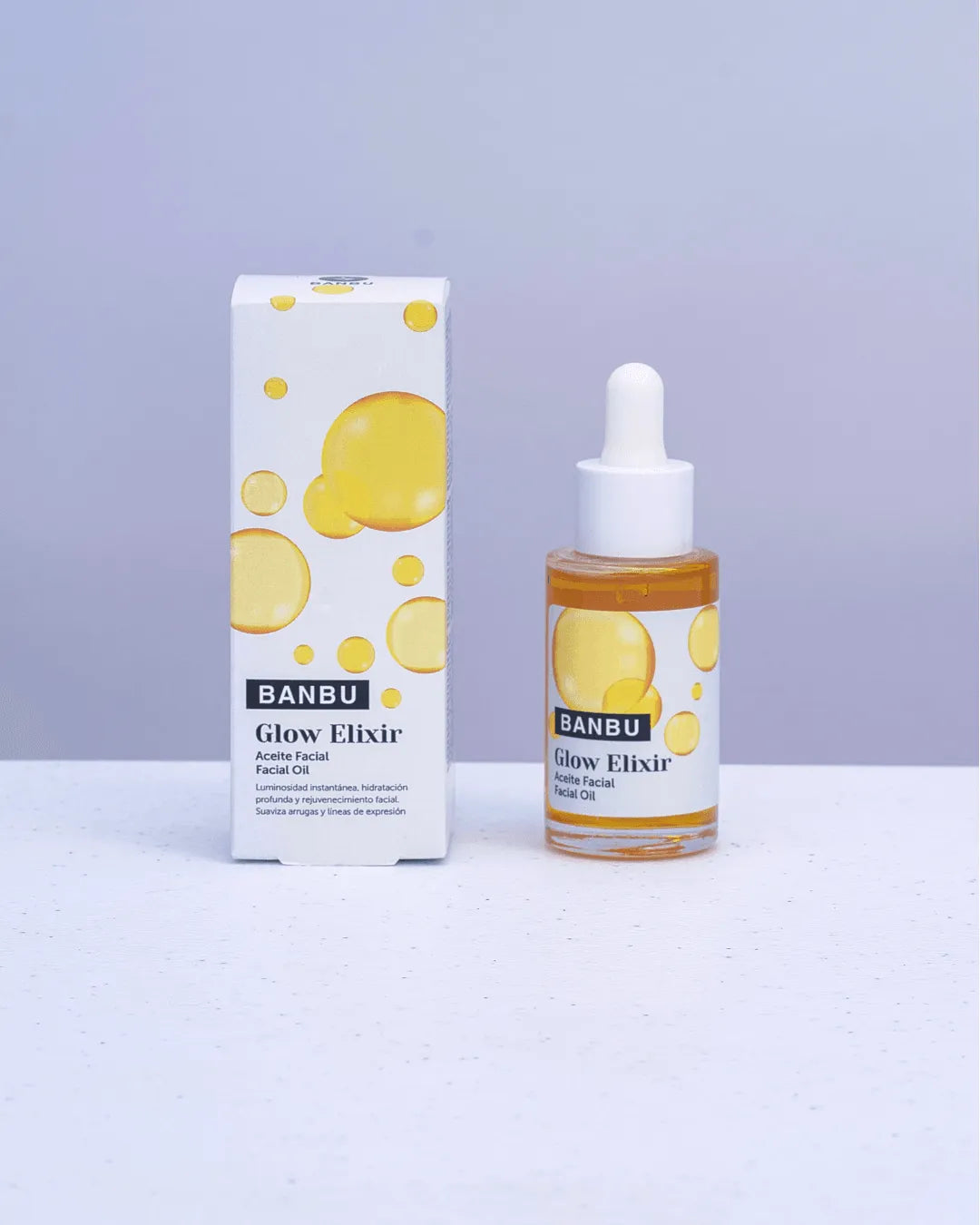Sérum facial Banbu Glow Elixir junto a su caja blanca con diseño de burbujas doradas sobre fondo neutro.