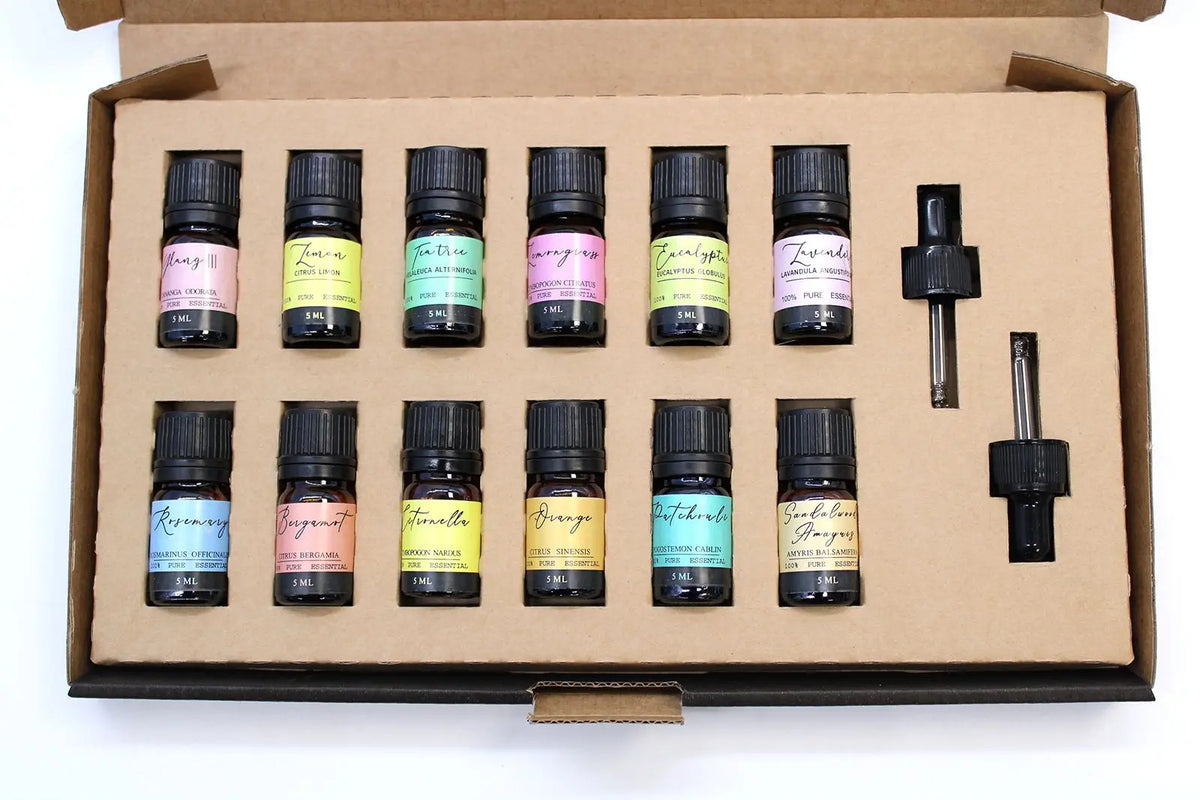 Set de 12 aceites esenciales en frascos de vidrio ámbar con etiquetas de colores y dos goteros en caja de cartón.
