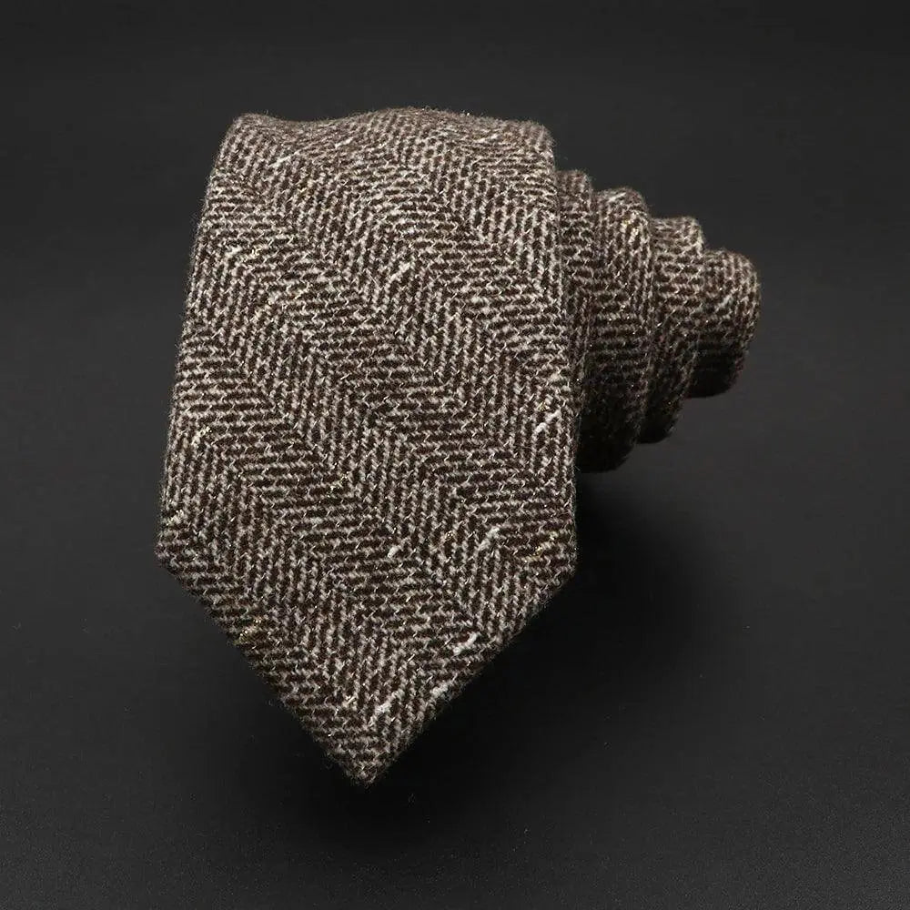Corbata enrollada de lana en color marrón con patrón de espiga y textura rústica sobre fondo negro.