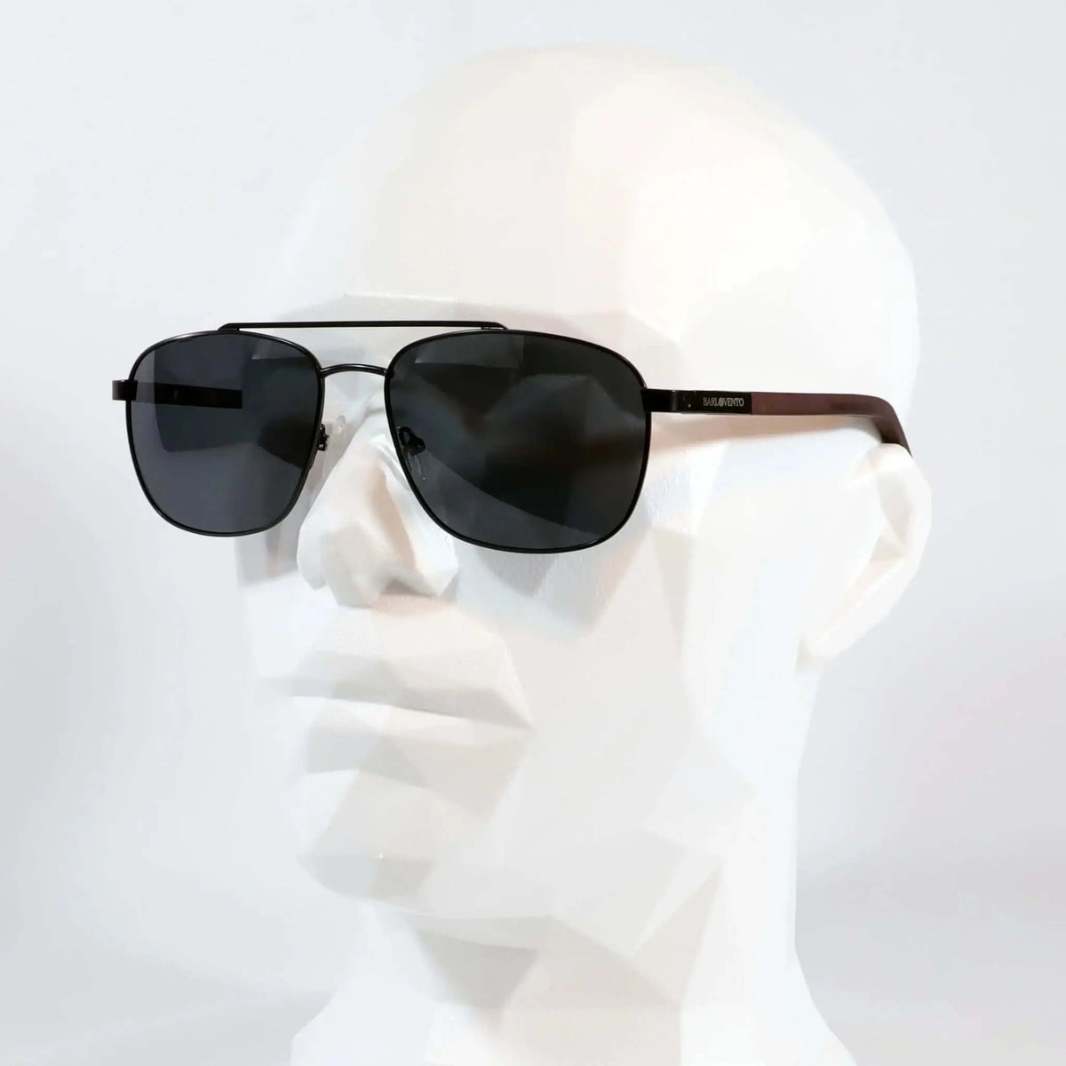 Gafas de sol estilo aviador con montura negra metálica, doble puente y patillas de madera oscura sobre maniquí blanco.