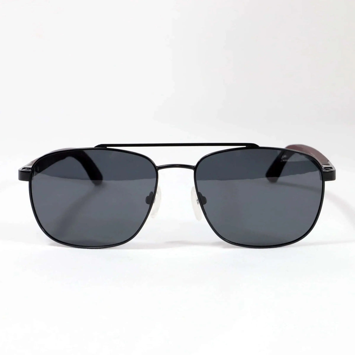 Gafas de sol estilo aviador con montura negra metálica, lentes oscuras y patillas de madera sobre fondo blanco.
