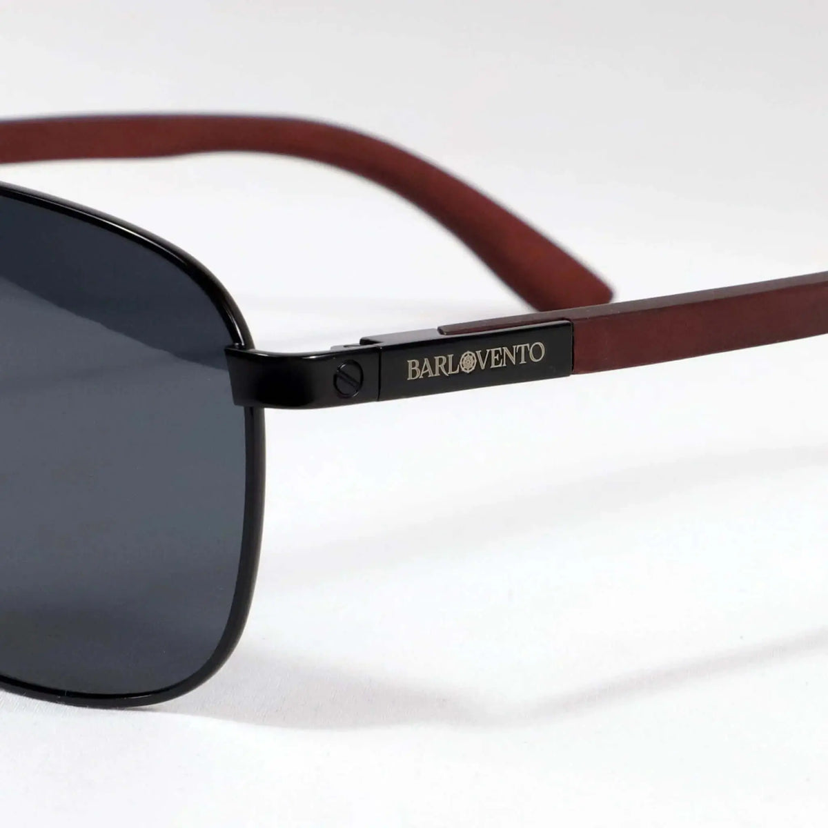 Gafas de sol con cristales oscuros, montura negra metálica y patillas de madera en tono rojizo sobre fondo blanco.
