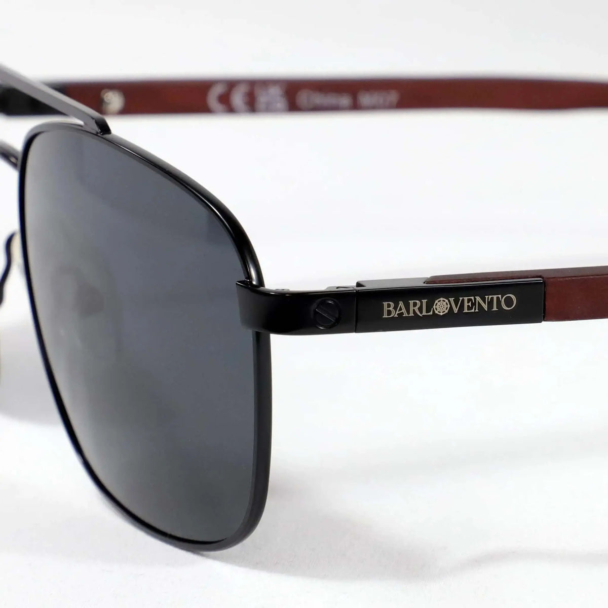 Gafas de sol estilo aviador con montura negra metálica, cristales oscuros y patillas de madera marrón.