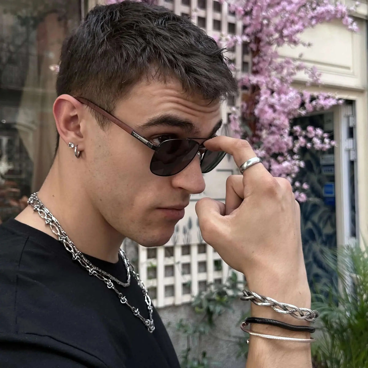 Gafas de sol estilo aviador con montura oscura y patillas de madera, puestas por un hombre con accesorios metálicos.