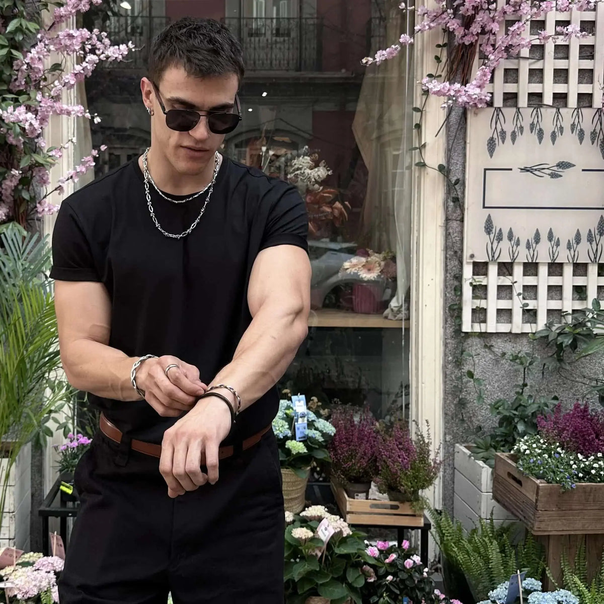 Gafas de sol negras con patillas de madera grabada, estilo moderno y elegante, usadas por un hombre con ropa casual.