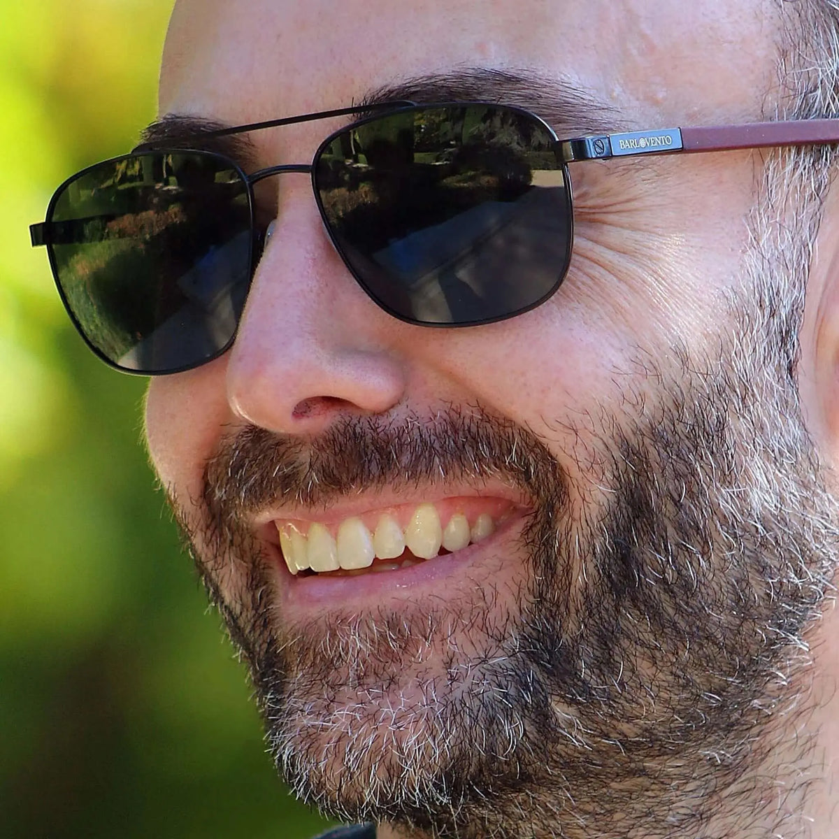 Gafas de sol estilo aviador con montura negra metálica, cristales oscuros y patillas de madera de color caoba.