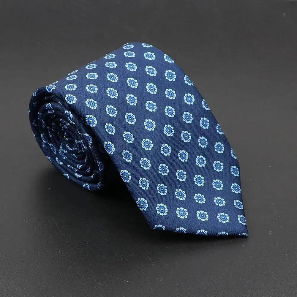Corbata azul marino enrollada con estampado de pequeñas flores blancas y azules sobre fondo oscuro.