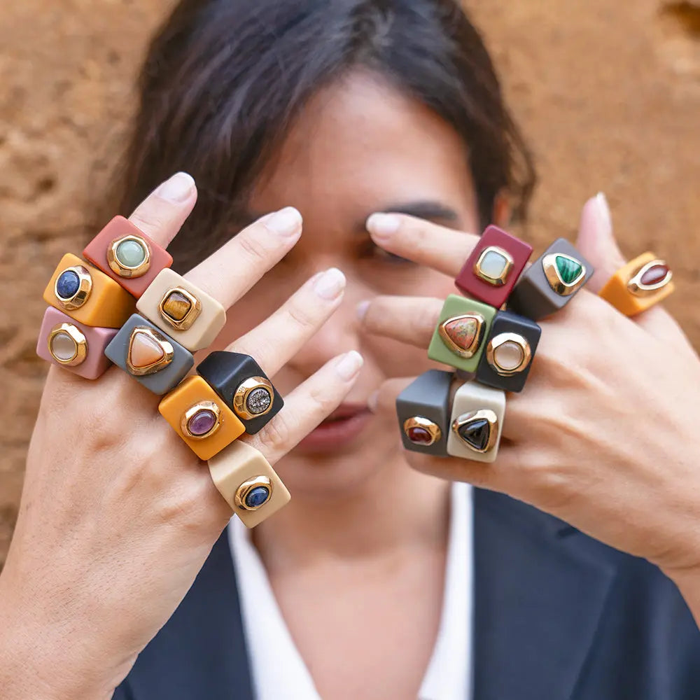 Anillos de resina en tonos terracota, negro, y gris, con piedras preciosas, estilo moderno y vanguardista.