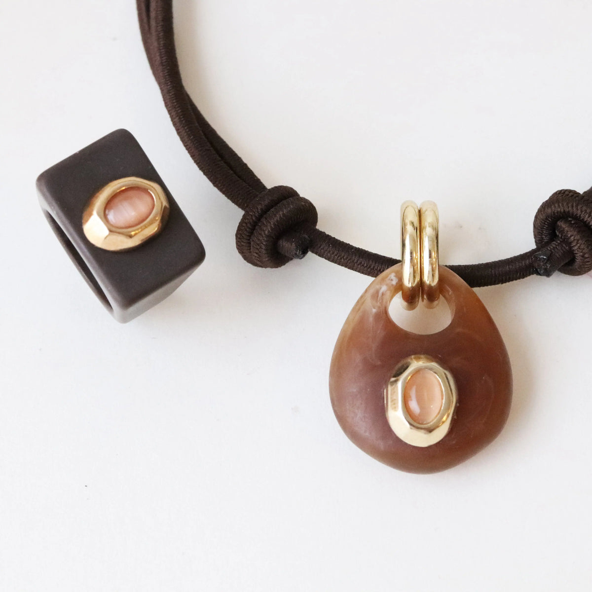 Collar de piedra marrón con detalle dorado y cuentas de cerámica negra en cordón ajustable.