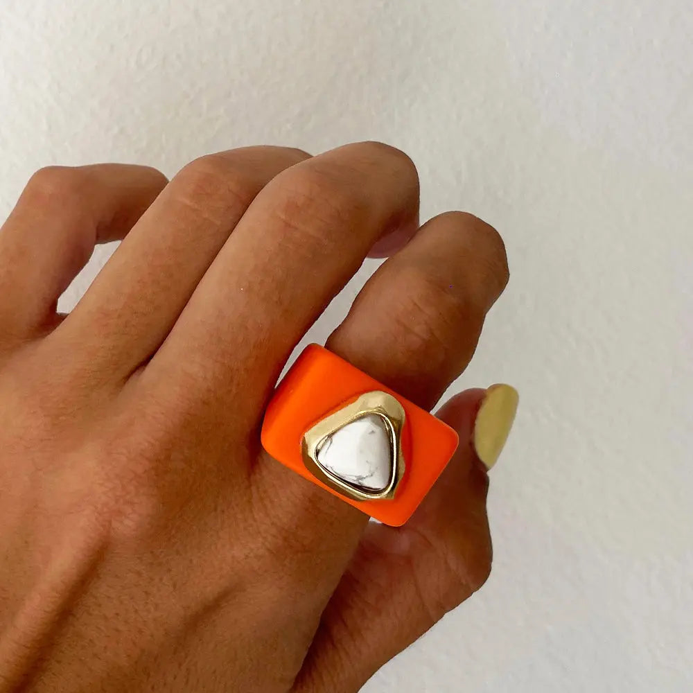Anillo moderno de silicona naranja con detalle en metal dorado en forma de triángulo. Ideal para un estilo vanguardista.