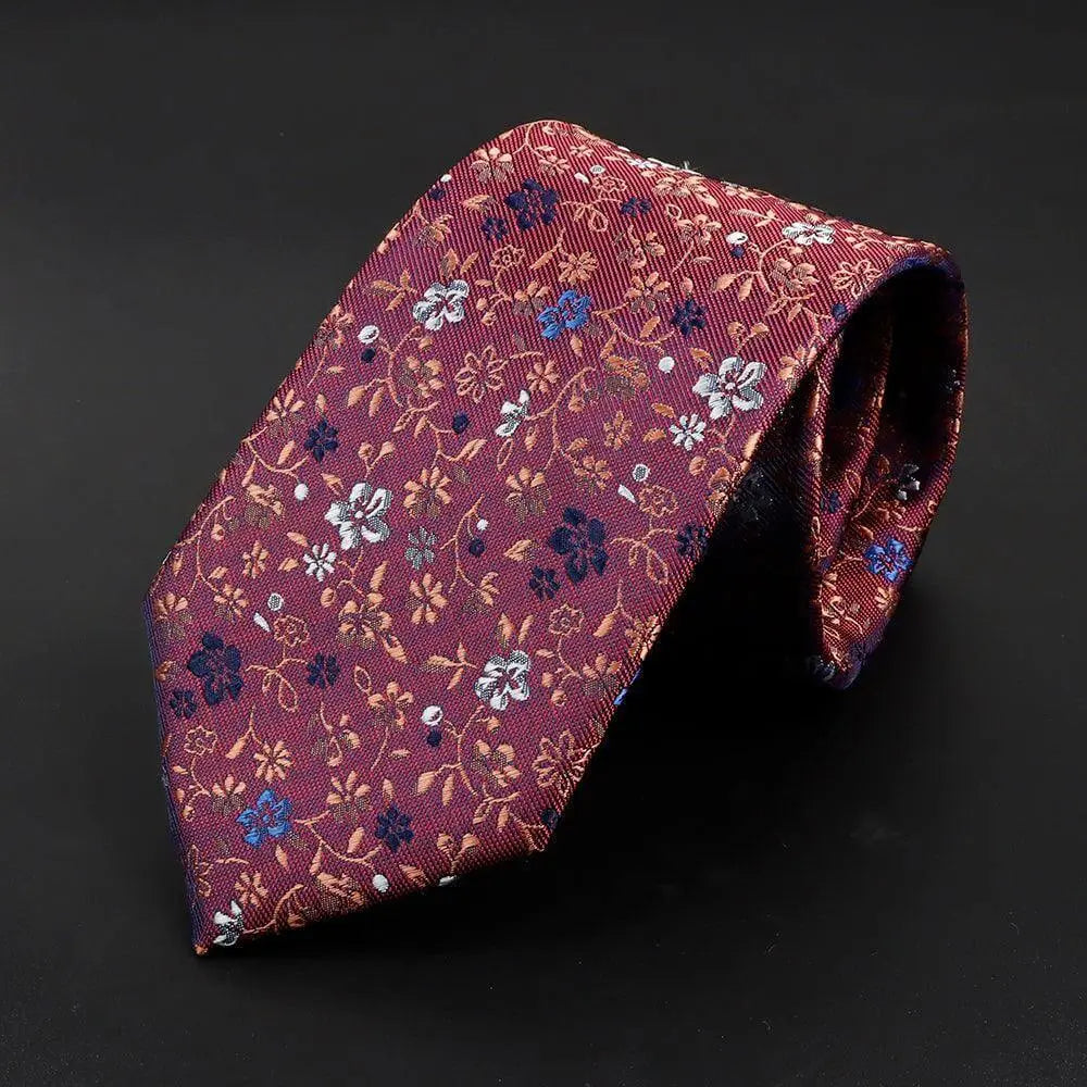 Corbata de seda color burdeos con un intrincado estampado floral en tonos azules, blancos y dorados.