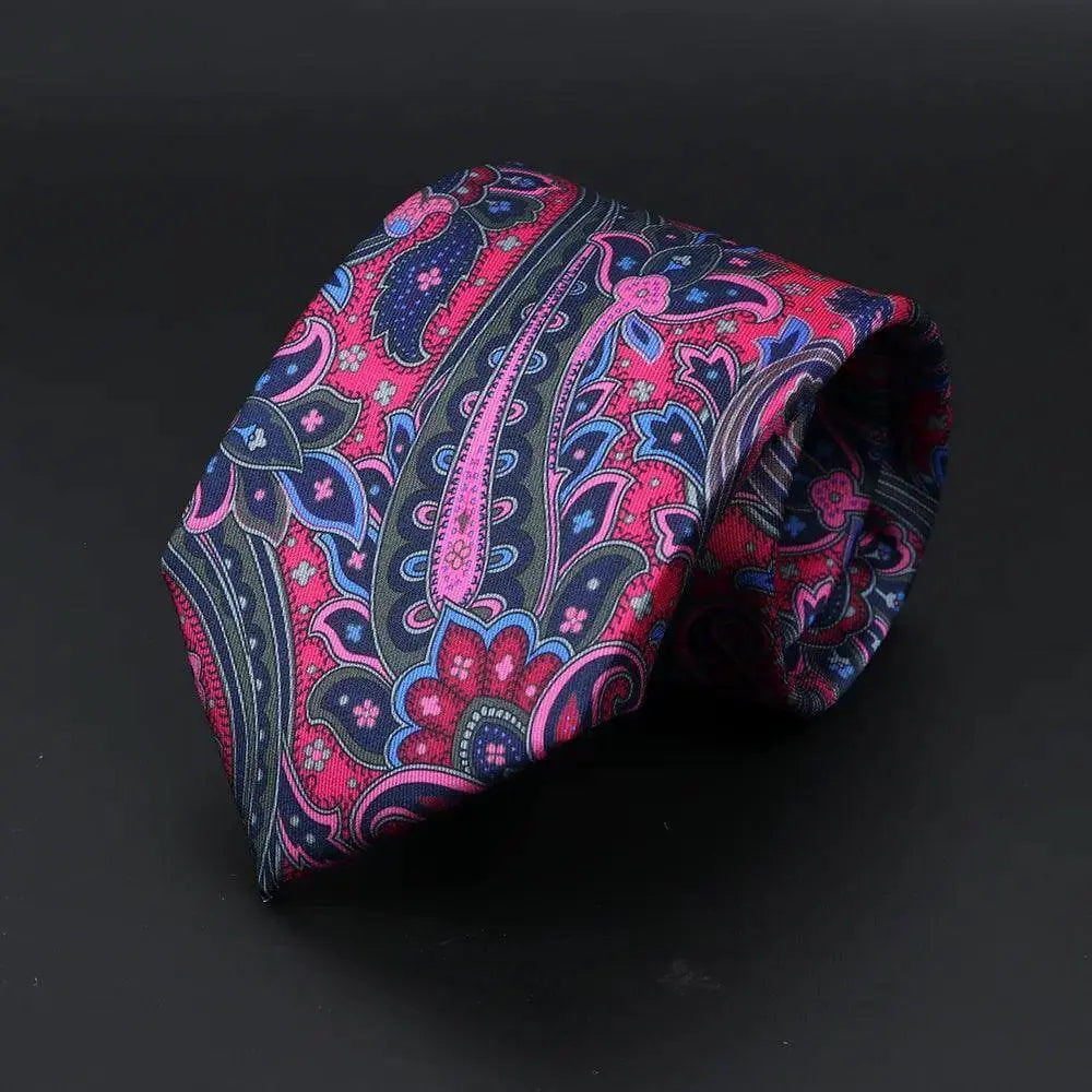 Corbata de seda con estampado paisley intrincado en tonos rosa vibrante, azul y negro sobre fondo oscuro.
