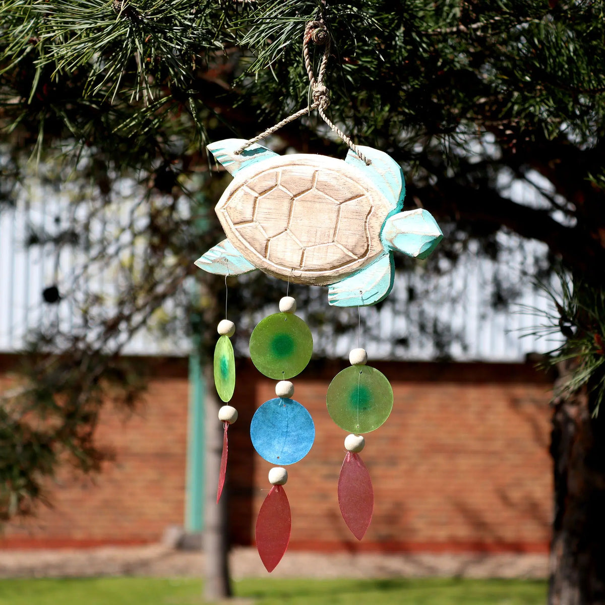 Carillón de madera con forma de tortuga azul, decorado con discos y gotas de cristal de colores colgantes.