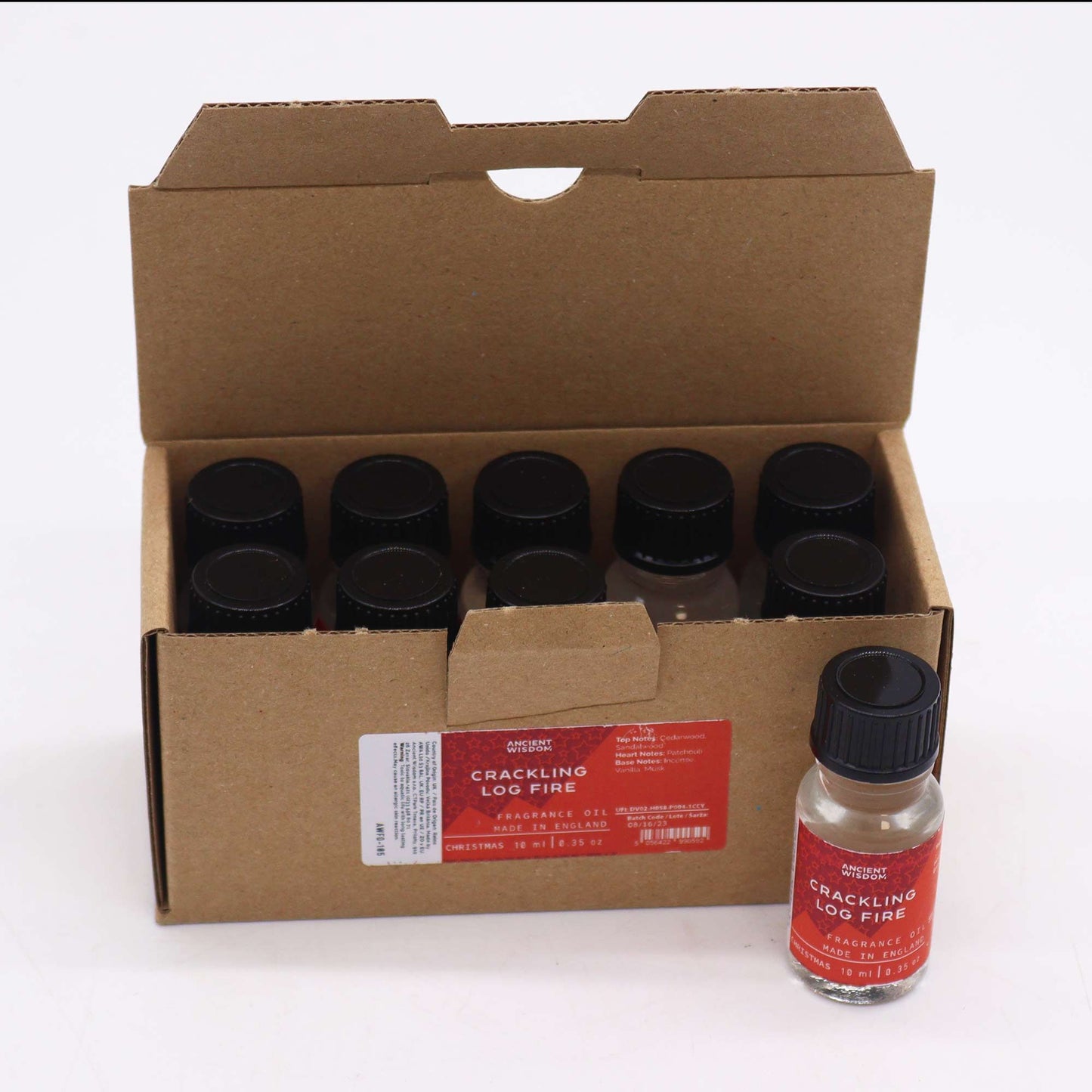Caja de cartón con 10 frascos de aceite aromático de 10ml, con etiquetas rojas y tapas negras. Un frasco está fuera.