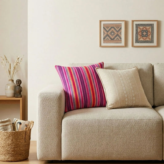 Cojines decorativos de colores rosa y beige sobre sofá gris claro en ambiente moderno y minimalista.