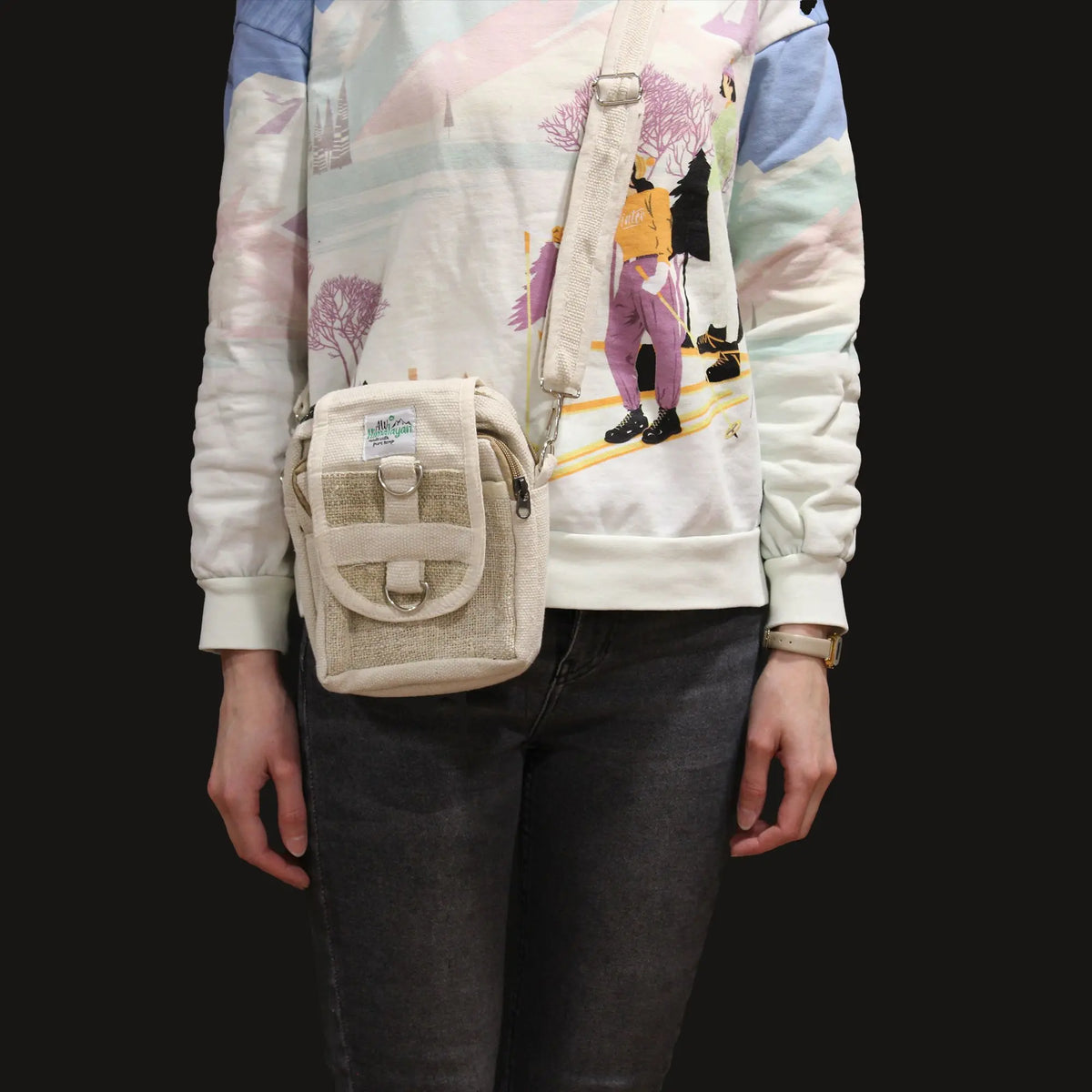 Bolsa cruzada beige de cáñamo y algodón, estilo artesanal con correas ajustables, usada por una persona de frente.