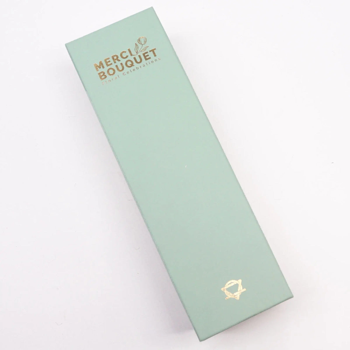 Caja rectangular alargada de color verde menta con detalles decorativos en letras doradas, sobre un fondo blanco.