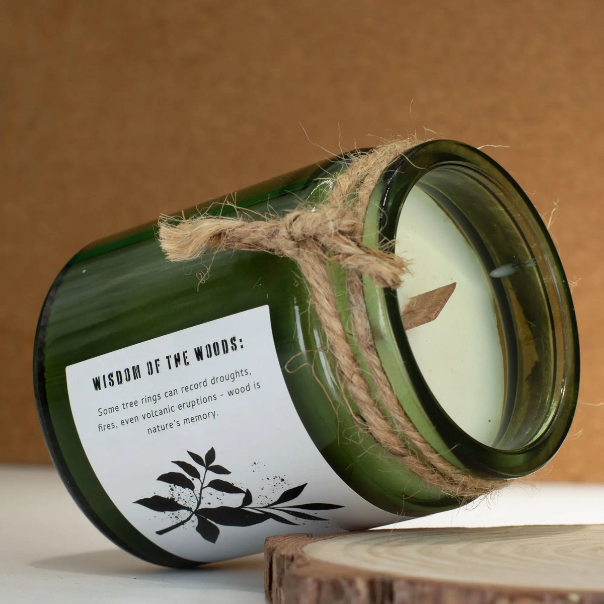 Vela aromática verde en frasco de vidrio, con etiqueta blanca y cuerda, estilo rústico y natural.