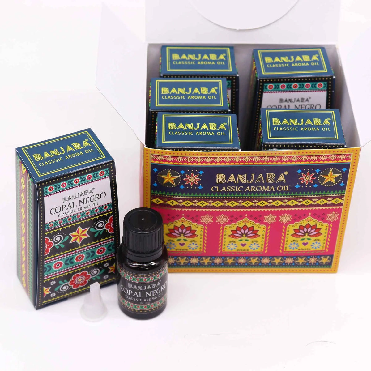 Cajas y frasco de aceite aromático con diseño colorido, estampado floral y motivos geométricos inspirados en la India.