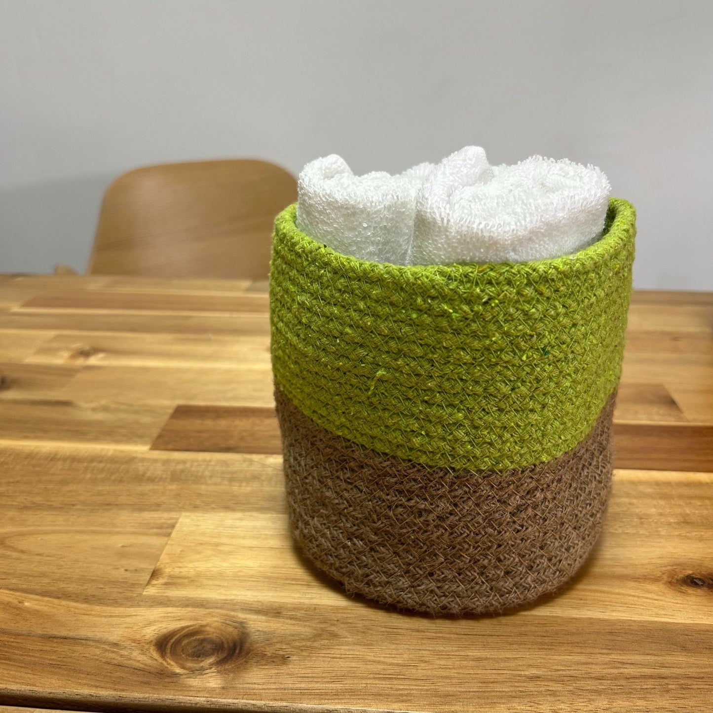 Cesta decorativa de yute verde y marrón, ideal para toallas, estilo rústico y moderno.