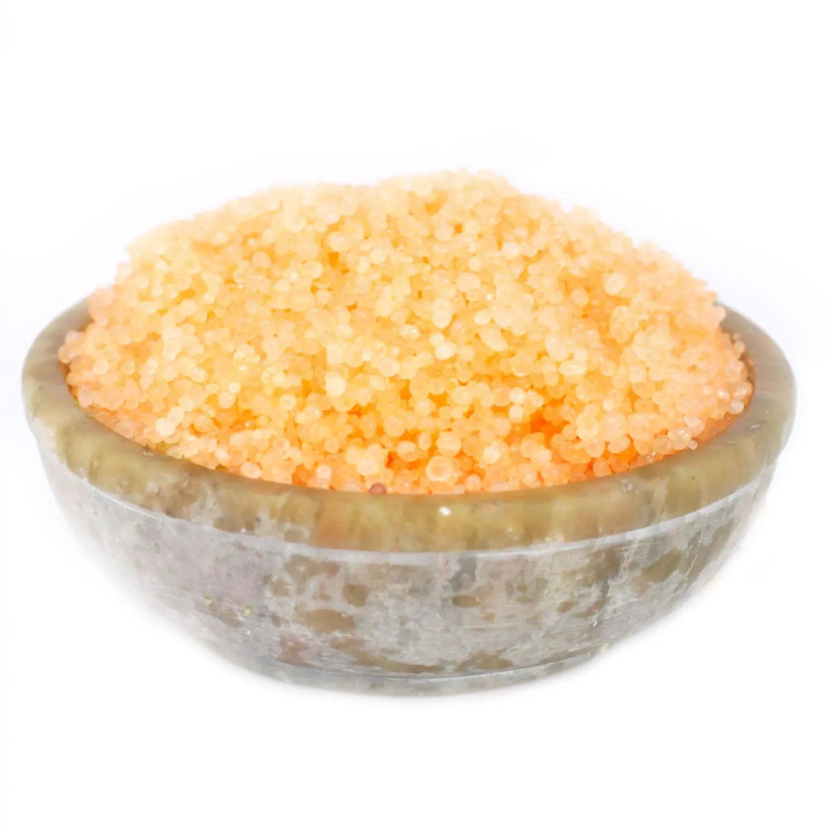 Cuenco de piedra gris lleno de pequeños gránulos aromáticos de color naranja brillante sobre fondo blanco.
