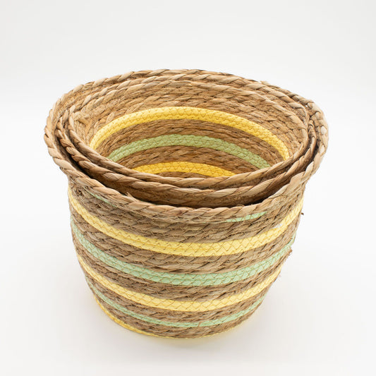 Juego de tres cestas tejidas de hierba marina con franjas decorativas en color amarillo y verde sobre fondo blanco.