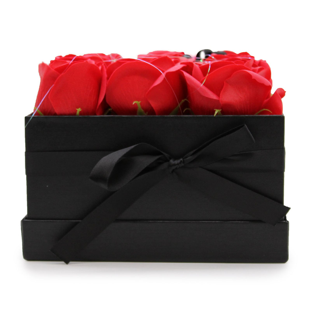 Caja negra cuadrada con lazo, conteniendo 9 rosas rojas hechas de jabón, sobre un fondo blanco.