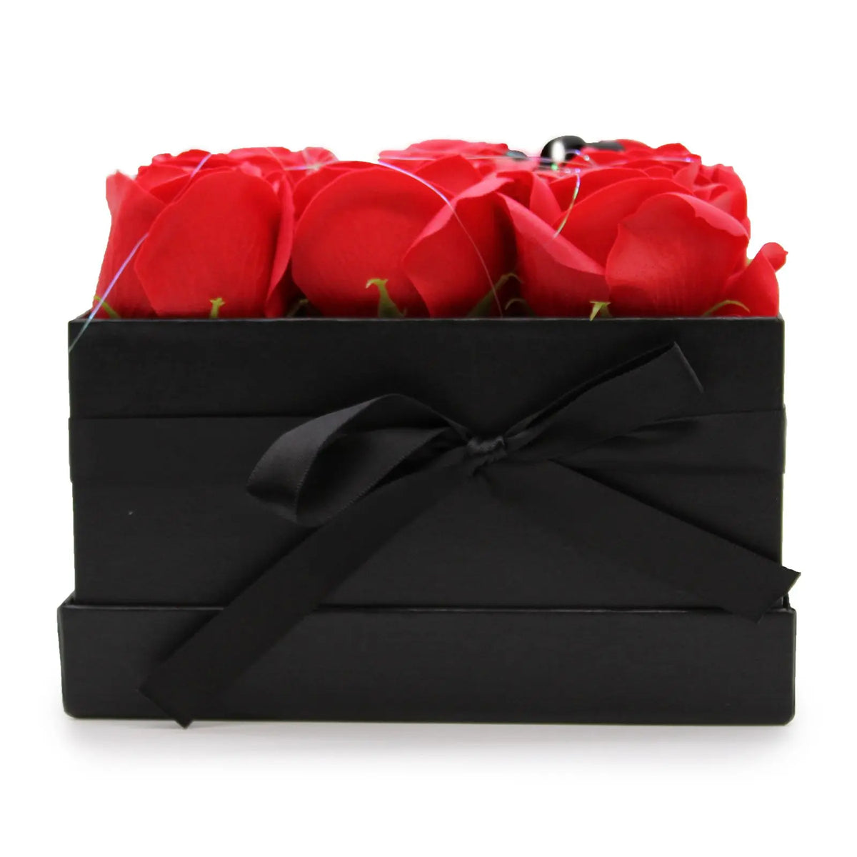 Caja negra cuadrada con lazo, conteniendo 9 rosas rojas hechas de jabón, sobre un fondo blanco.