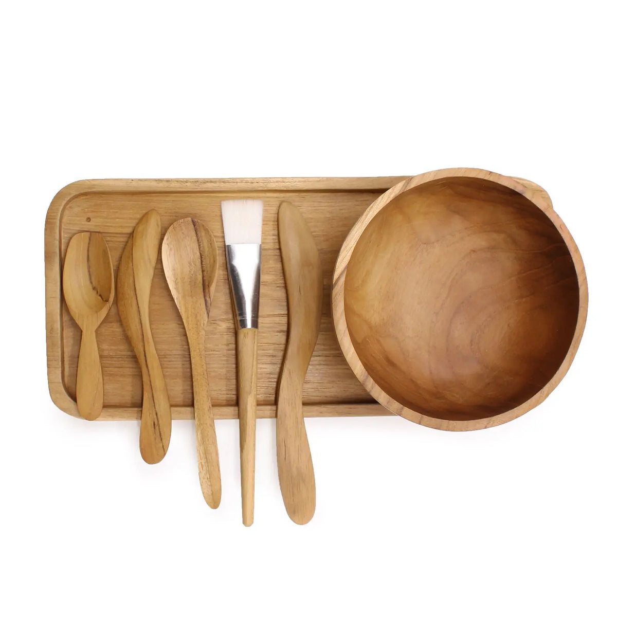 Kit de spa en madera de teca: cuenco, bandeja, espátulas y brocha sobre fondo blanco. Estilo artesanal y natural.