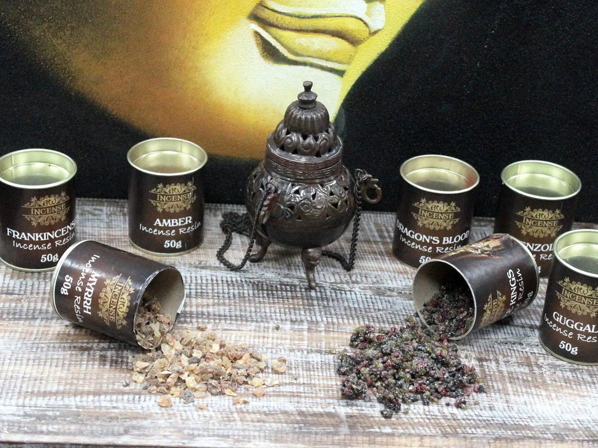 Latas redondas con resina de incienso aromático, junto a un quemador de metal sobre una superficie de madera envejecida