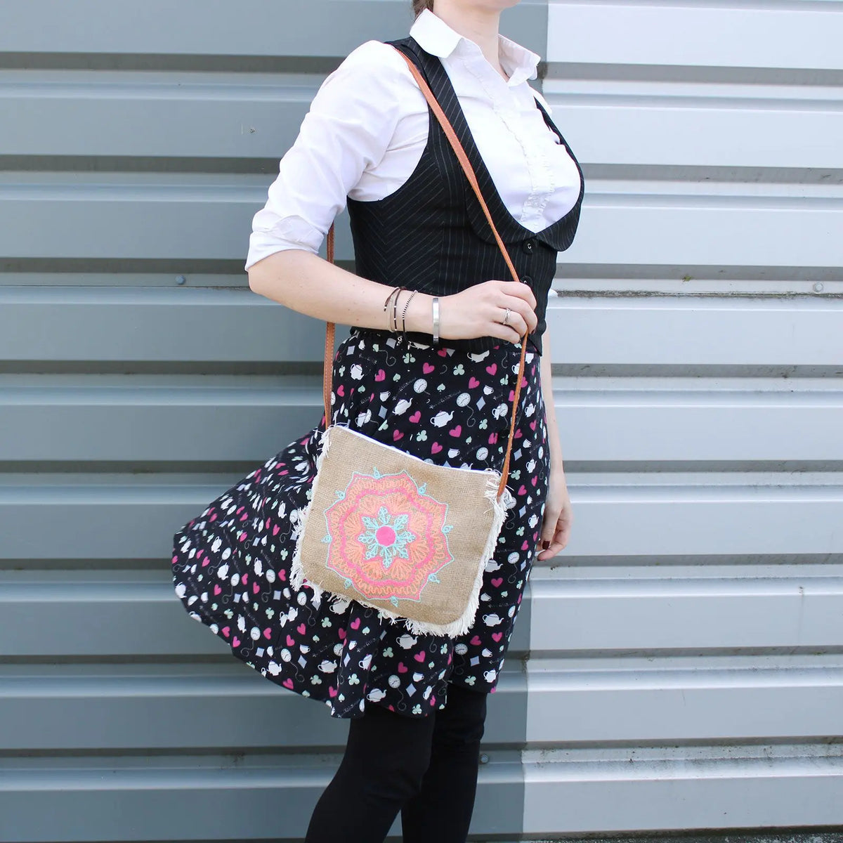 Bolso bandolera de yute con flecos y un colorido bordado de mandala en tonos rosa, naranja y turquesa.