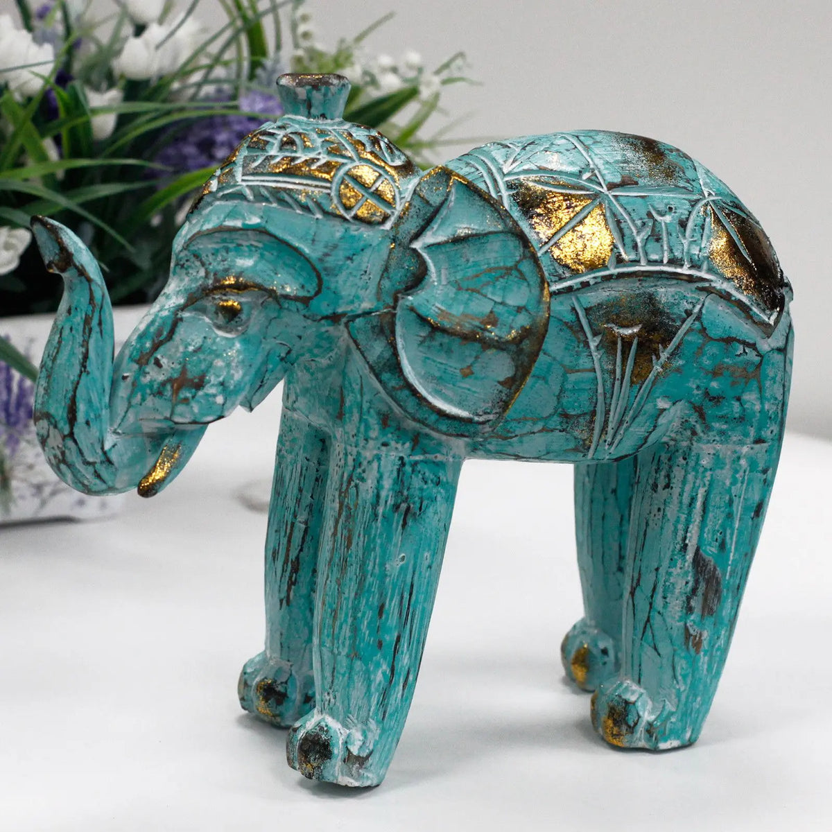 Elefante decorativo de cerámica turquesa con detalles dorados y estilo étnico. Ideal para decoración del hogar.