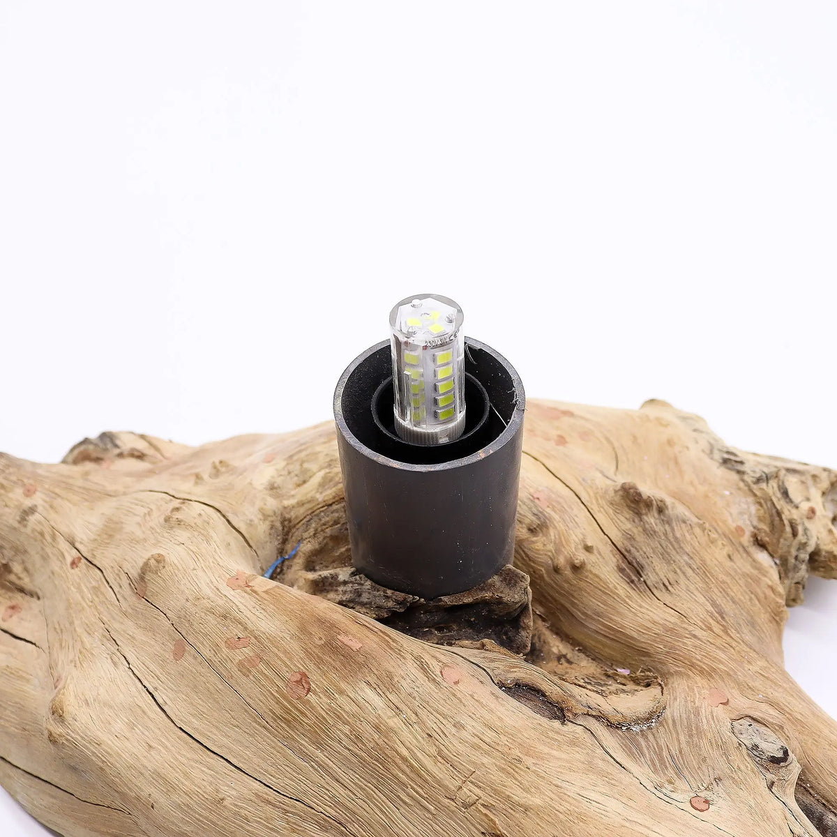 Base de lámpara rústica de madera natural con soporte cilíndrico negro y bombilla LED expuesta, sobre fondo blanco.