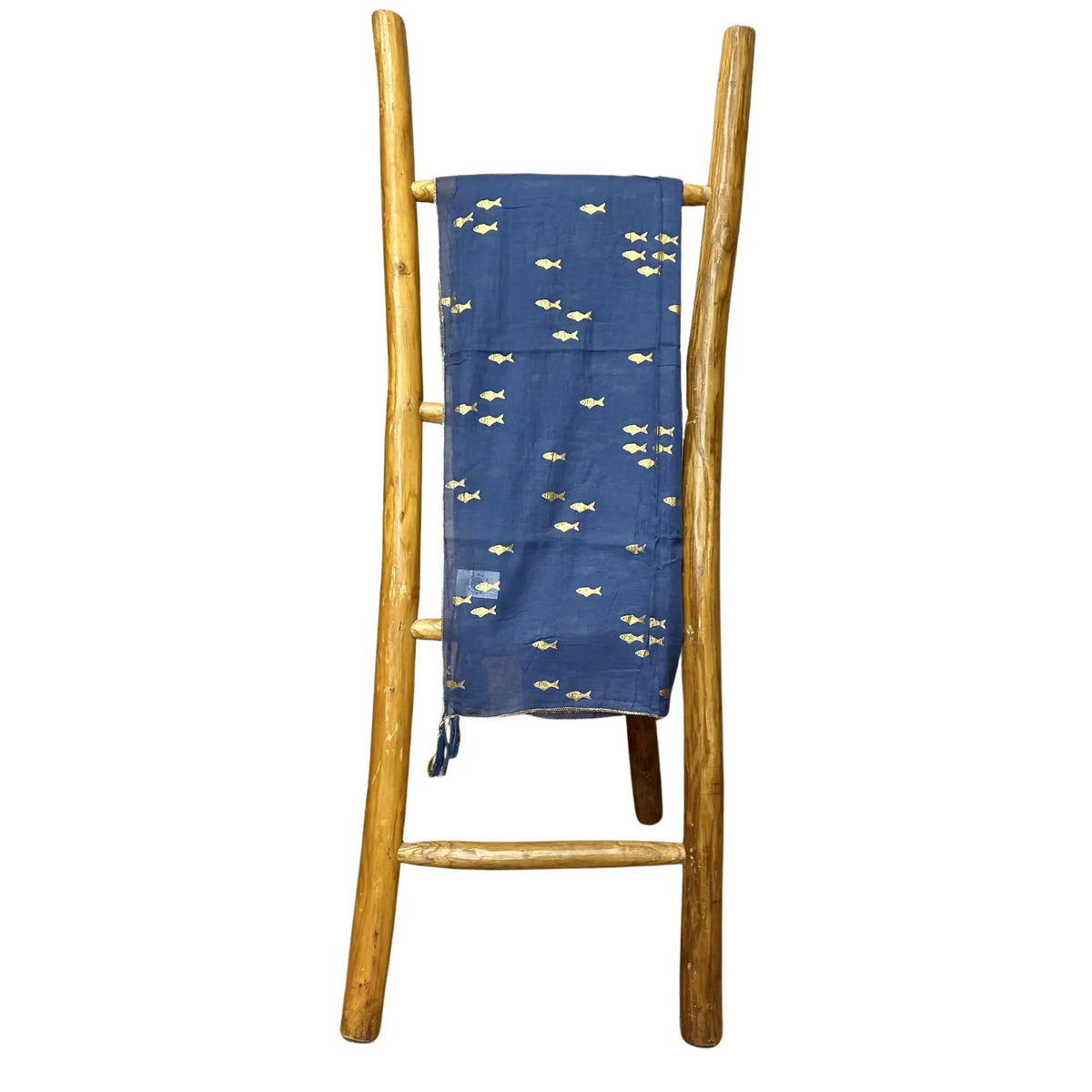 Pareo azul marino con estampado de peces dorados, colgado en una escalera decorativa de madera sobre fondo blanco.