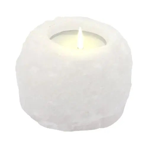 Portavelas de sal del Himalaya blanca, forma circular irregular y textura rugosa con vela encendida en su interior.