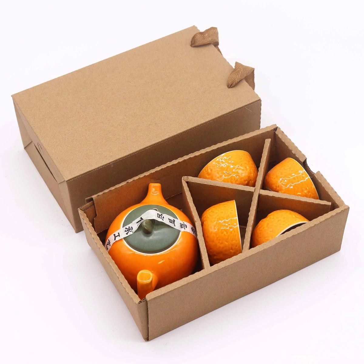 Juego de tetera y cuatro tazas de cerámica naranja con textura de piel de fruta, en caja de regalo de cartón.