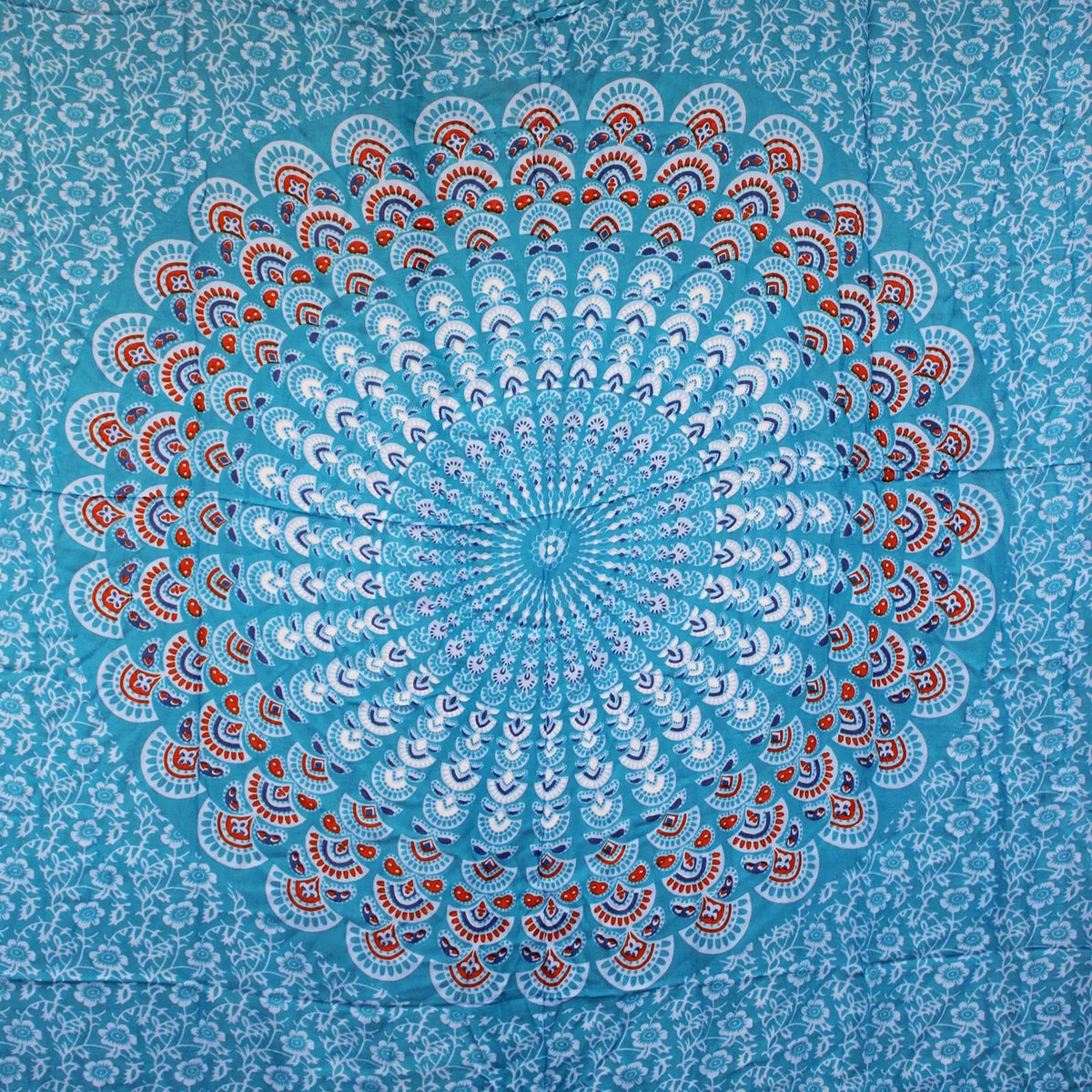 Pareo con estampado de mandala circular en tonos verde azulado y naranja sobre fondo floral. Estilo bohemio.