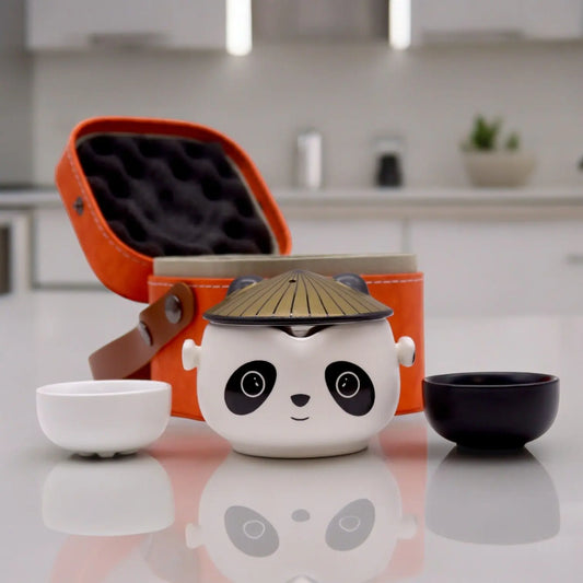 Set de té de cerámica estilo panda con dos tazas, una blanca y una negra, y estuche de viaje naranja protector