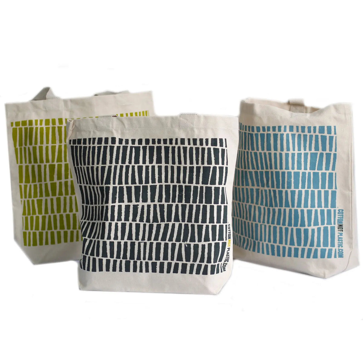 Tres bolsas de algodón color crema con estampados de rectángulos en verde, negro y azul sobre fondo blanco.