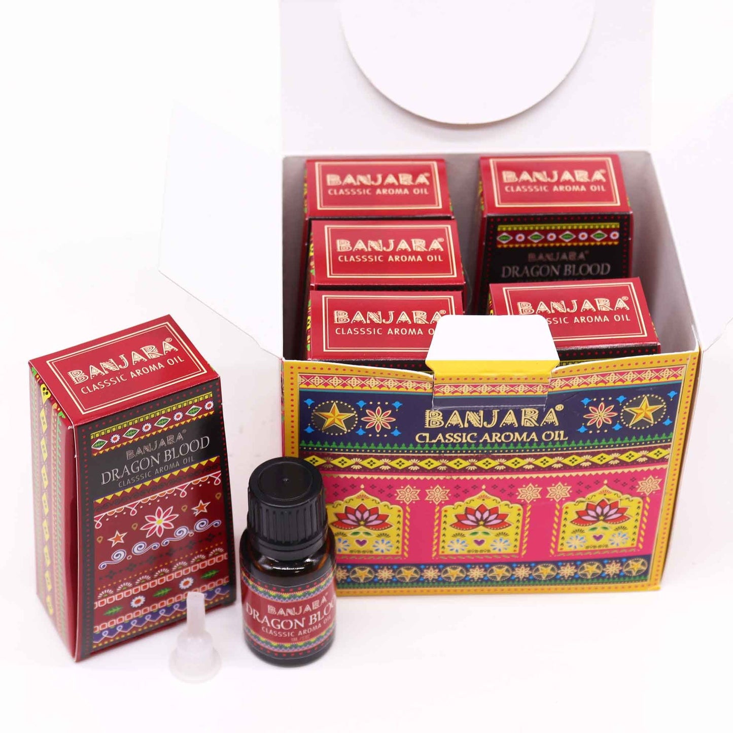 Caja abierta y frasco de aceite aromático con diseño decorativo colorido y motivos florales en tonos rojos y dorados.