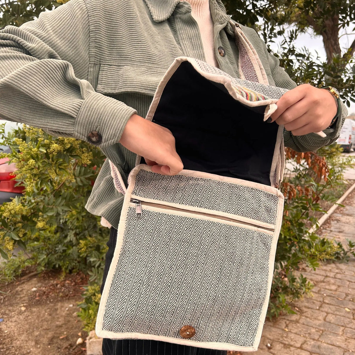 Bolso mensajero de cáñamo con patrón de espiga, solapa abierta, bolsillo frontal con cremallera y detalle de botón.