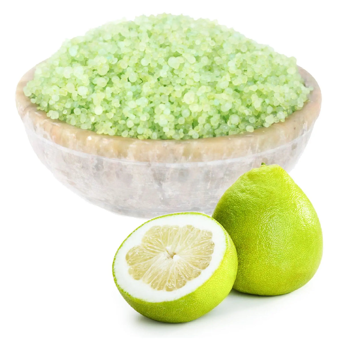 Cuenco de piedra con gránulos aromáticos de color verde junto a un pomelo entero y otro cortado a la mitad.