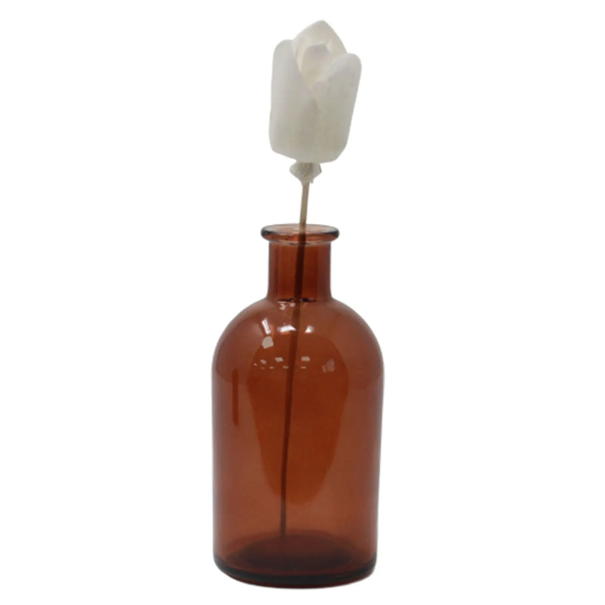 Flor de madera blanca tipo tulipán sobre varilla en botella de vidrio ámbar, usada como difusor de fragancias.