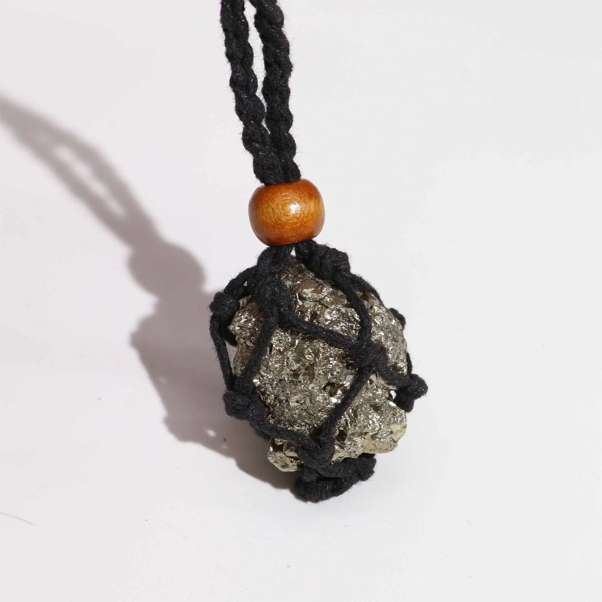 Collar de cordón negro tejido tipo red con cuenta de madera, sosteniendo una piedra pirita metálica de forma irregular.
