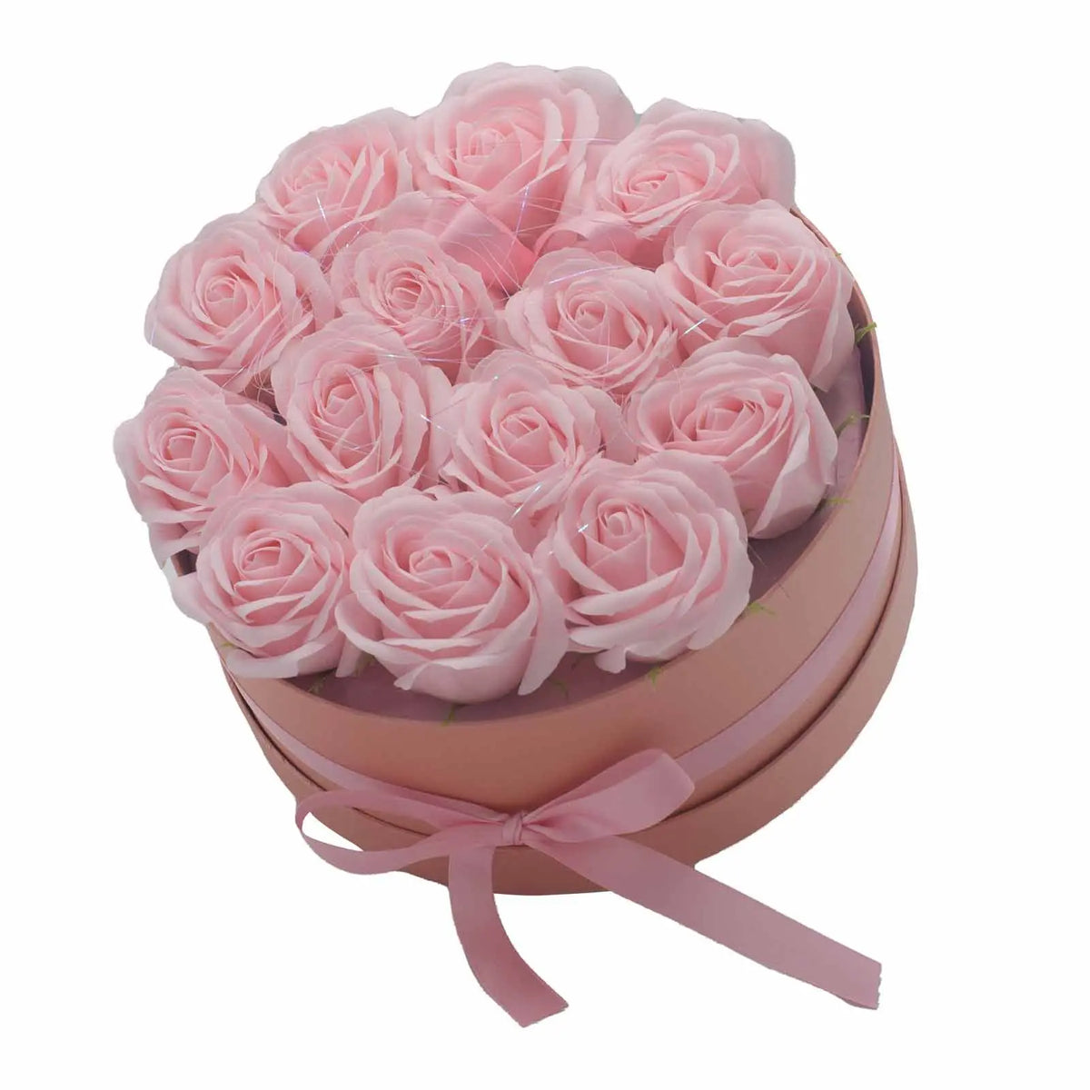 Caja redonda rosa con 14 rosas de jabón rosadas, decorada con un lazo de cinta del mismo color.