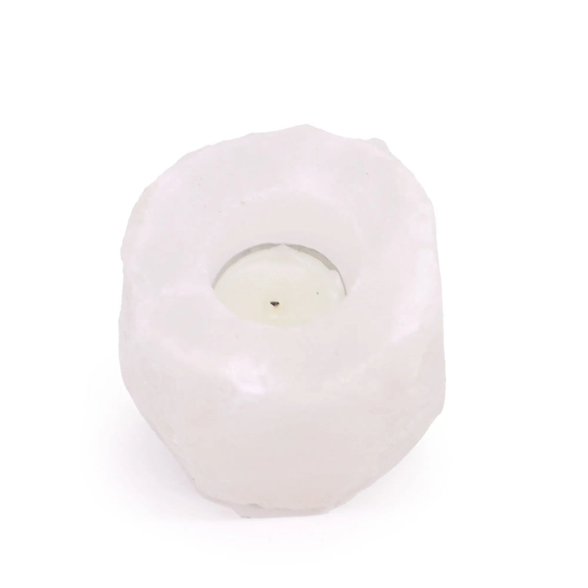Portavelas de sal del Himalaya blanco, forma irregular y rocosa con una vela en su interior sobre fondo blanco.