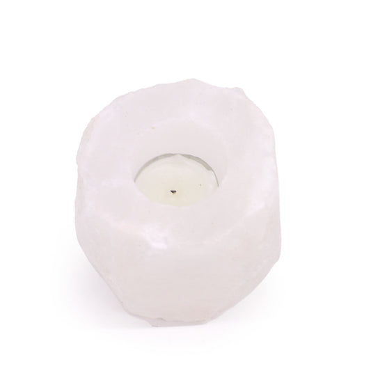 Portavelas de sal del Himalaya blanco, forma irregular y rocosa con una vela en su interior sobre fondo blanco.